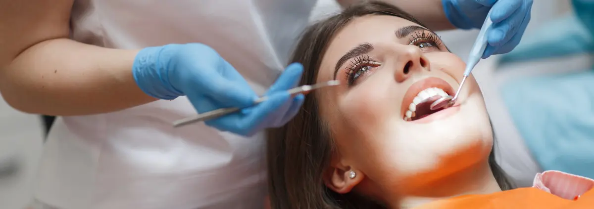 Eine junge Frau liegt auf dem Behandlungsstuhl während ihr die Zahnspange entfernt wird