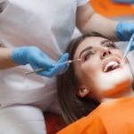 Eine junge Frau liegt auf dem Behandlungsstuhl während ihr die Zahnspange entfernt wird