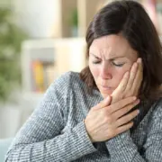 aeltere frau haelt sich die haende an die wange aufgrund von Zahnspangen schmerzen