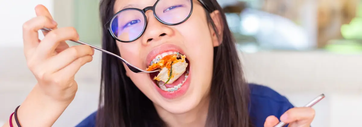 junge frau isst mit brackets eine pizza