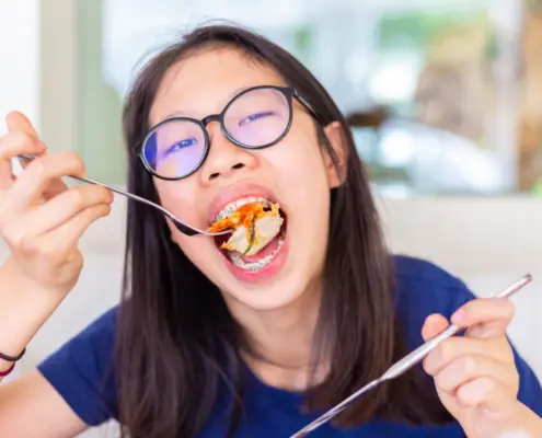 junge frau isst mit brackets eine pizza