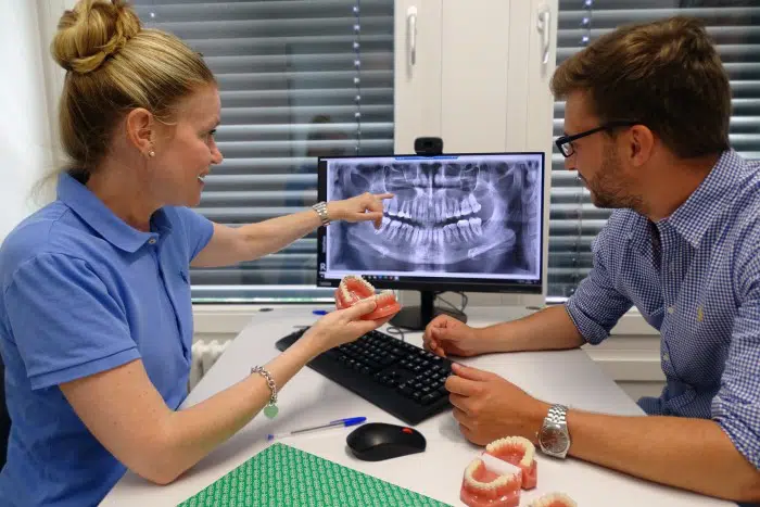 Kieferorthopädin und Patient bei der Planbesprechung, Kieferorthopädin erläutert Röntgenbild