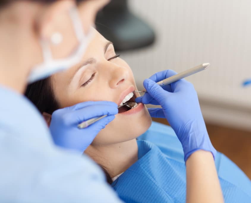 Einer jungen Frau werden während der Vorsorgeuntersuchung die Zähne professionell gereinigt